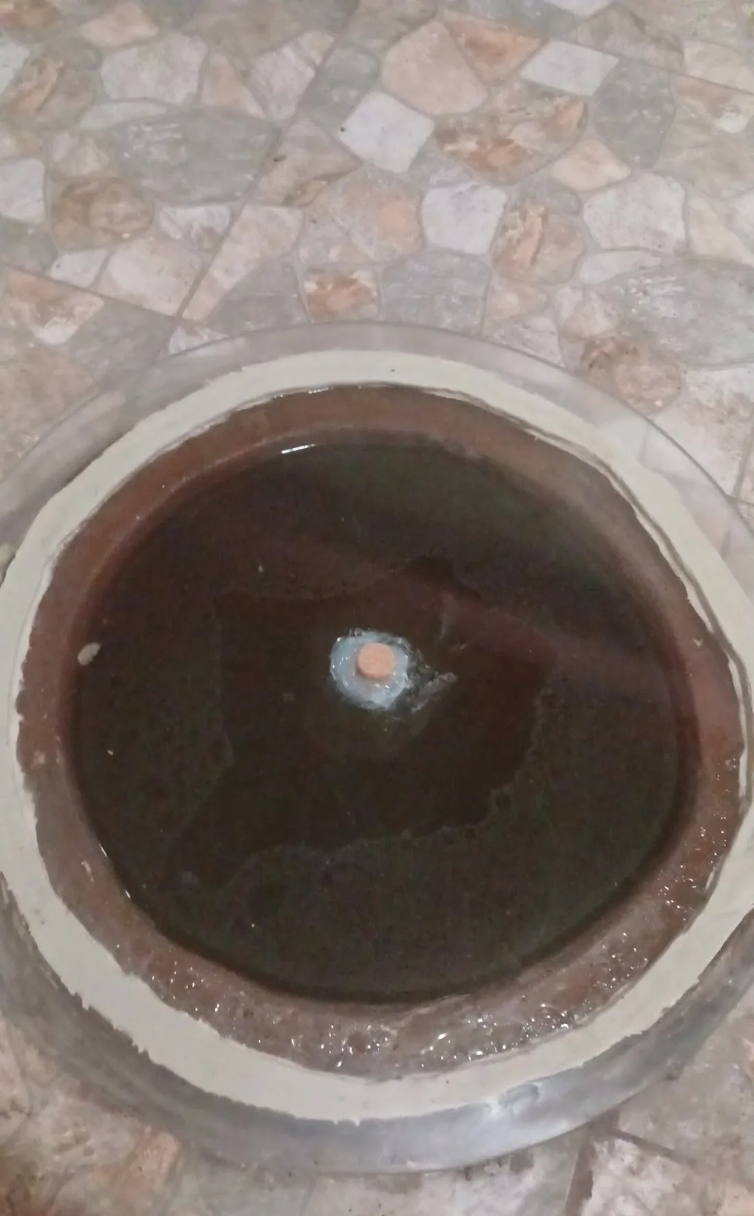A qvevri sealed with a round stone lid and clay while the wine rests underground